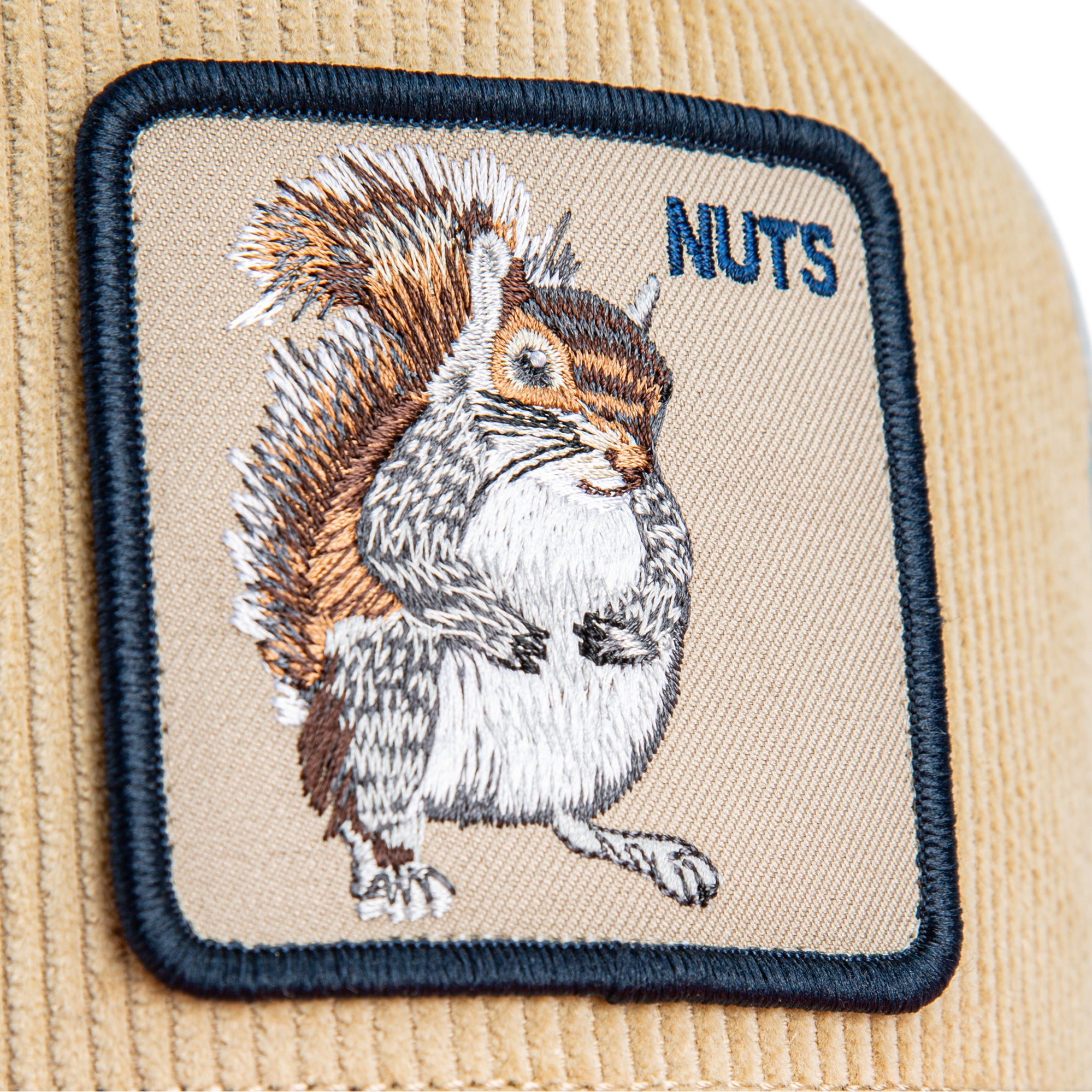 Beige, blue, and orange Goorin Bros trucker hat with corduroy front featuring embroidered squirrel patch labeled NUTS on front panel