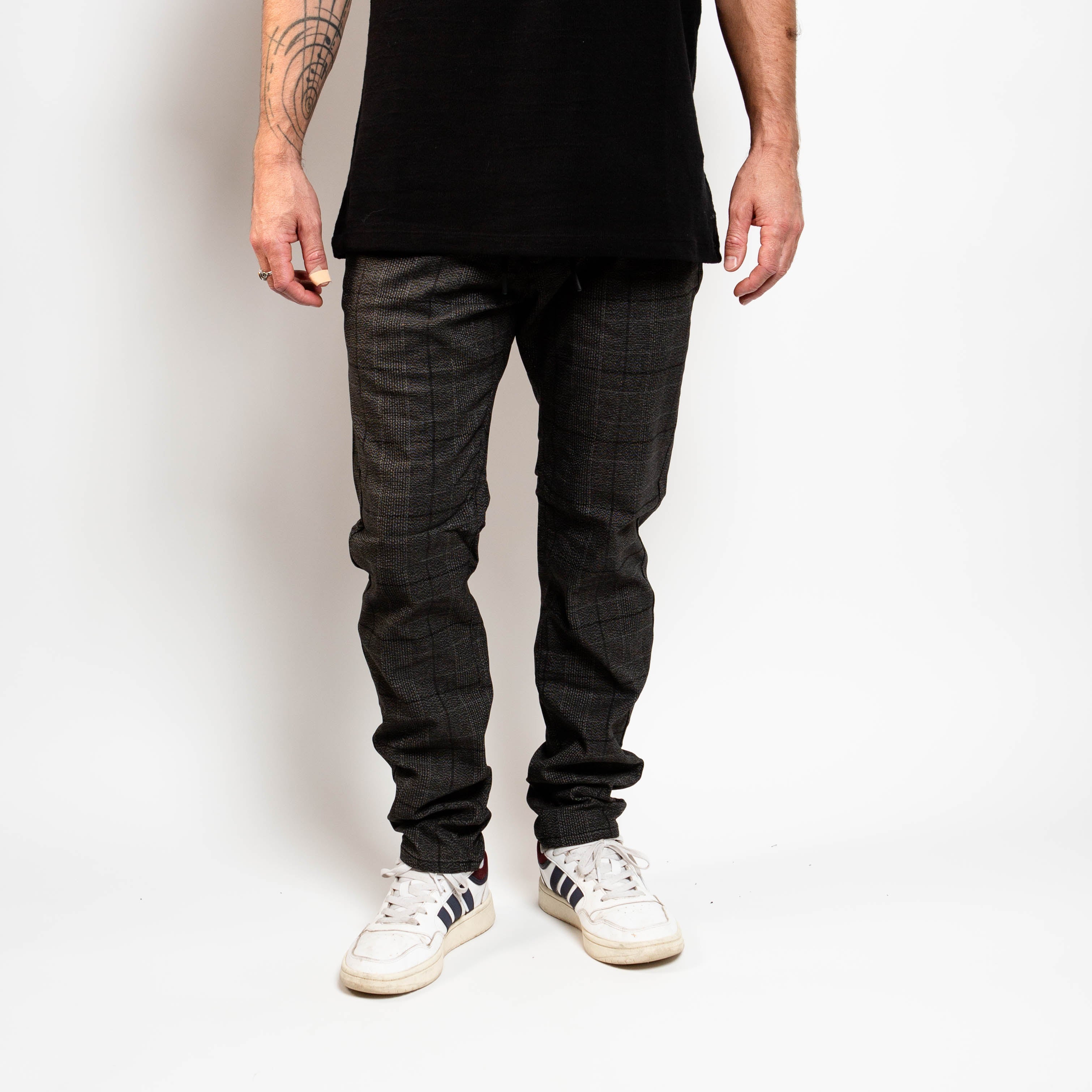Person wearing dark jeans and white sneakers on a plain background By Projek Raw
