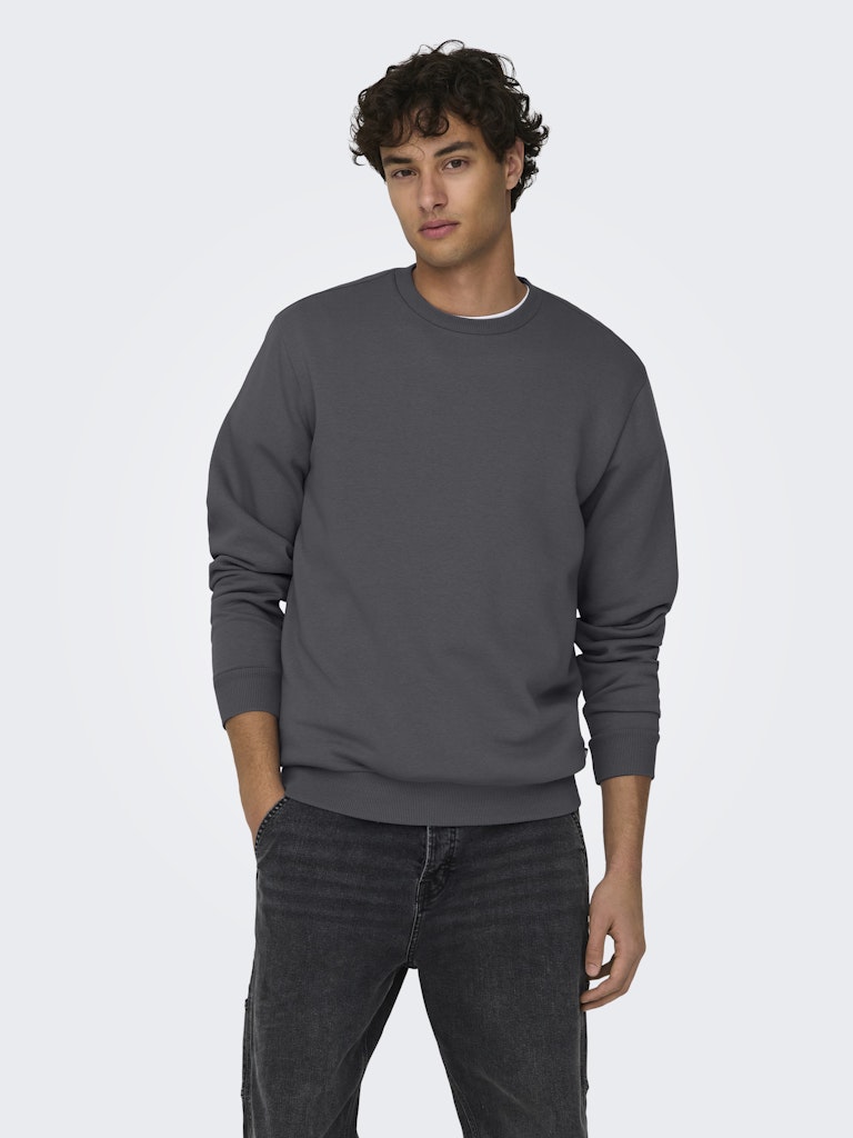 Man wearing a gray sweatshirt and dark jeans on a white background By Only & Sons