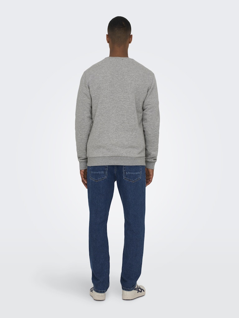 Person wearing a gray sweater and blue jeans on a white background By Only & Sons