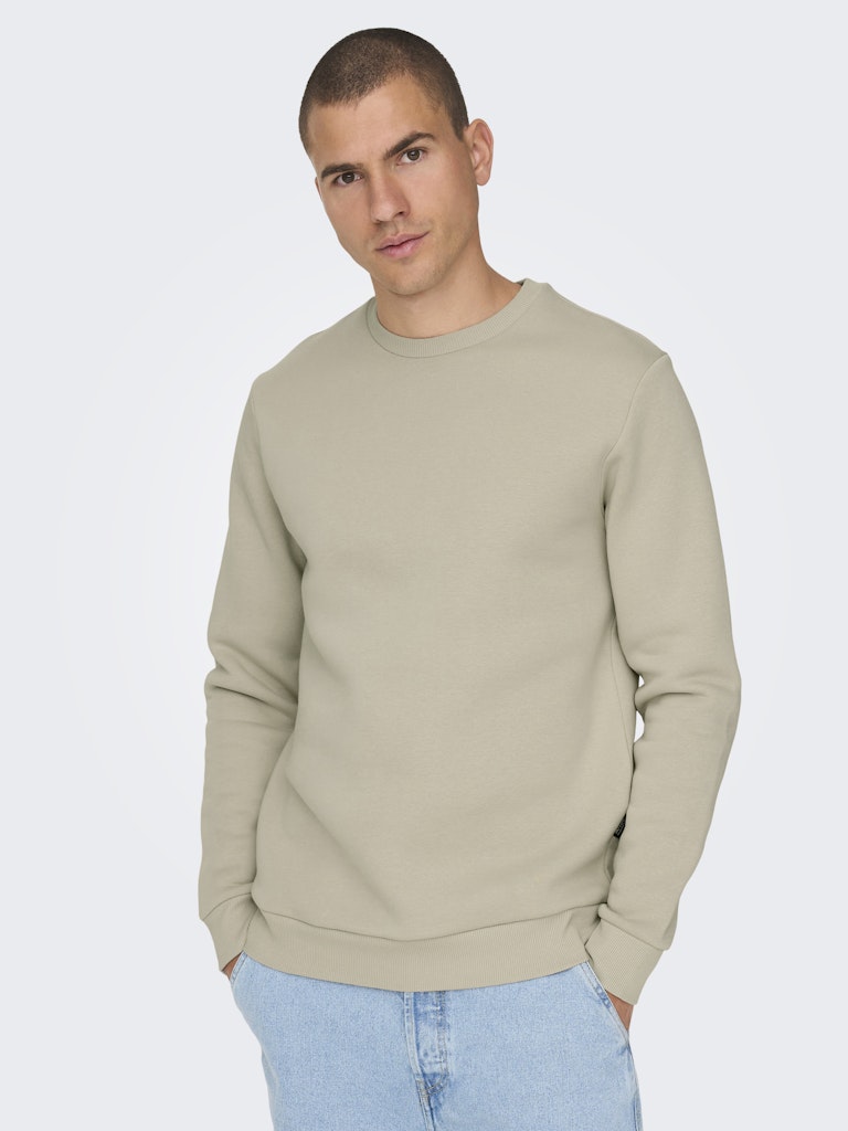 Man wearing a beige sweatshirt on a light gray background By Only & Sons