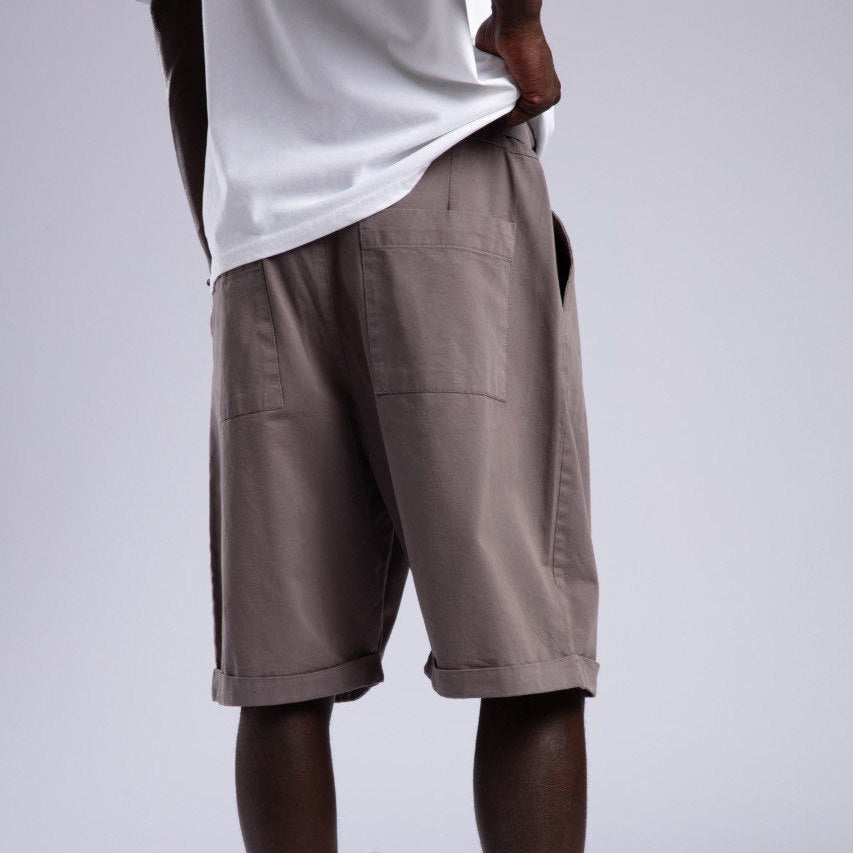 Person wearing brown shorts, white socks, and white sneakers on a plain background