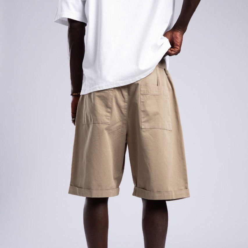 Person wearing beige shorts and a white t-shirt on a plain background
