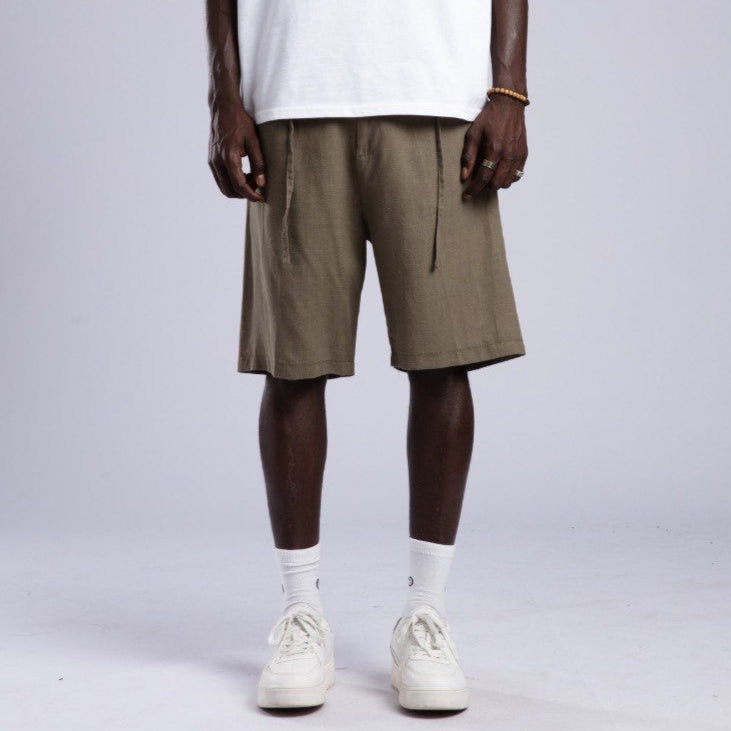 Person wearing a white t-shirt and olive shorts on a plain background