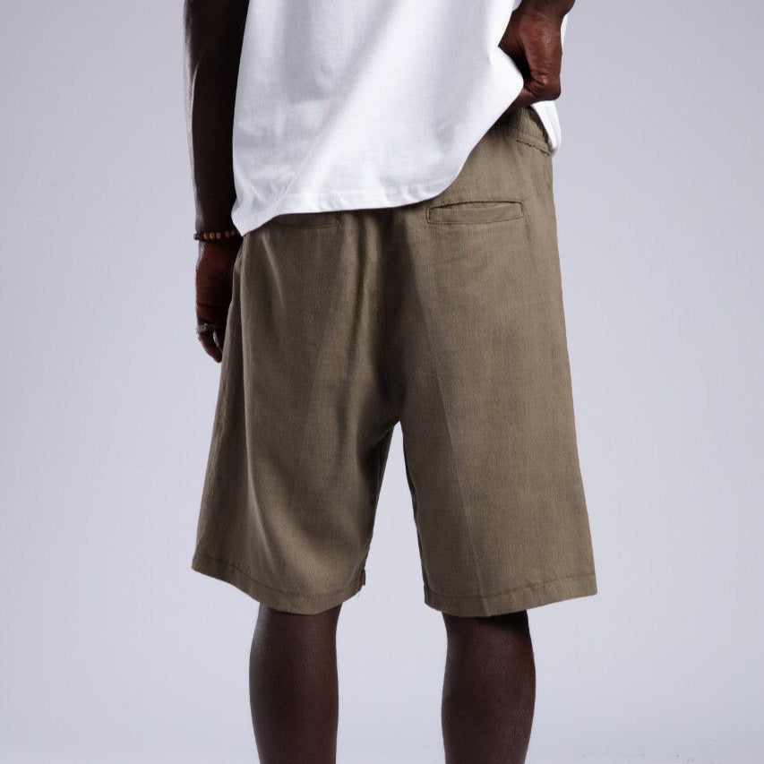 Person wearing brown shorts and white shoes on a plain background