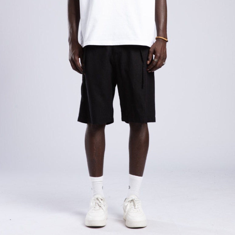 Person wearing a white t-shirt, black shorts, and white sneakers on a plain background