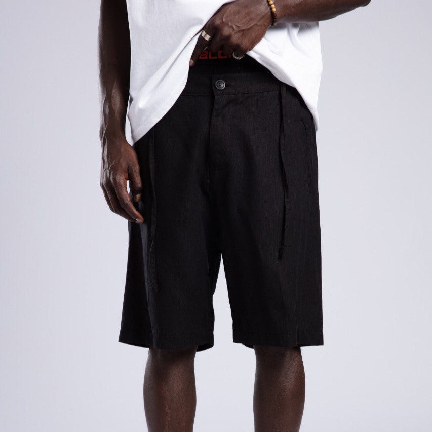 Person wearing black shorts, white shirt, and white sneakers on a light gray background