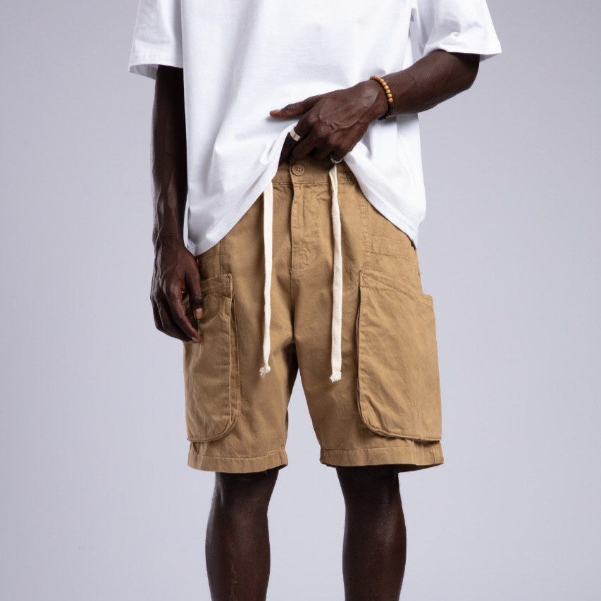 Person wearing beige cargo shorts and a white t-shirt on a plain background