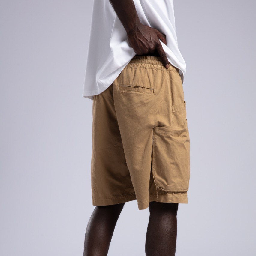 Person wearing beige cargo shorts and white sneakers on a light gray background
