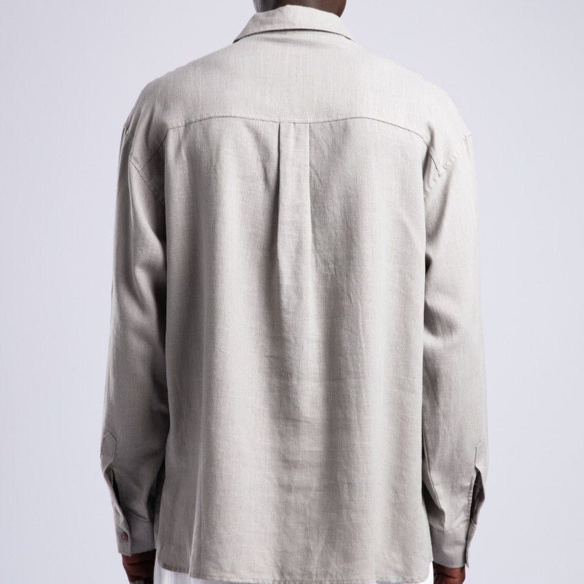 Person wearing a beige shirt and white pants against a plain background