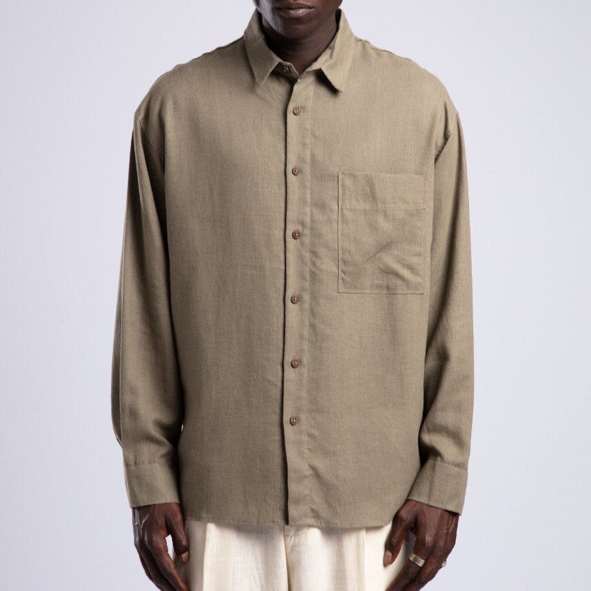 Man wearing a beige button-up shirt and sunglasses on a white background