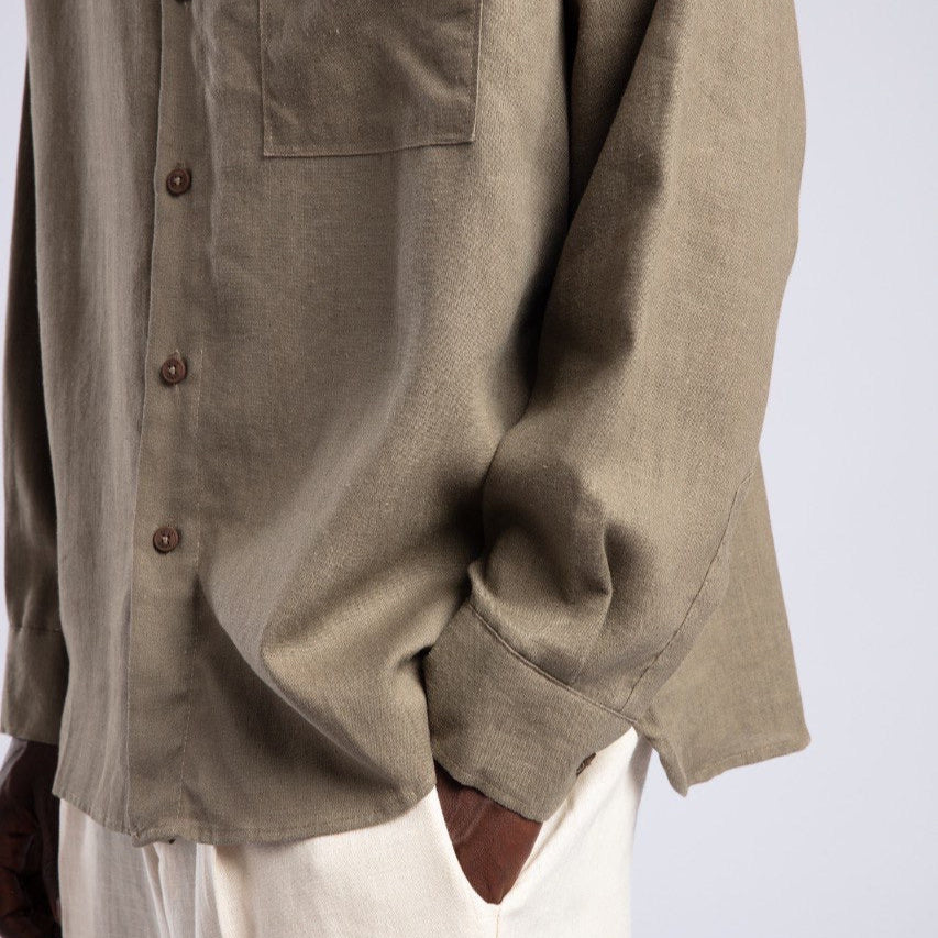 Close-up of a person wearing a beige shirt and white pants on a light gray background