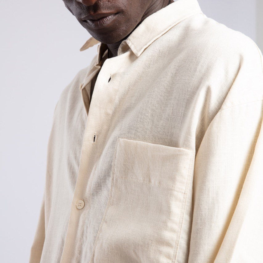 Man wearing a beige shirt with sunglasses on a plain background