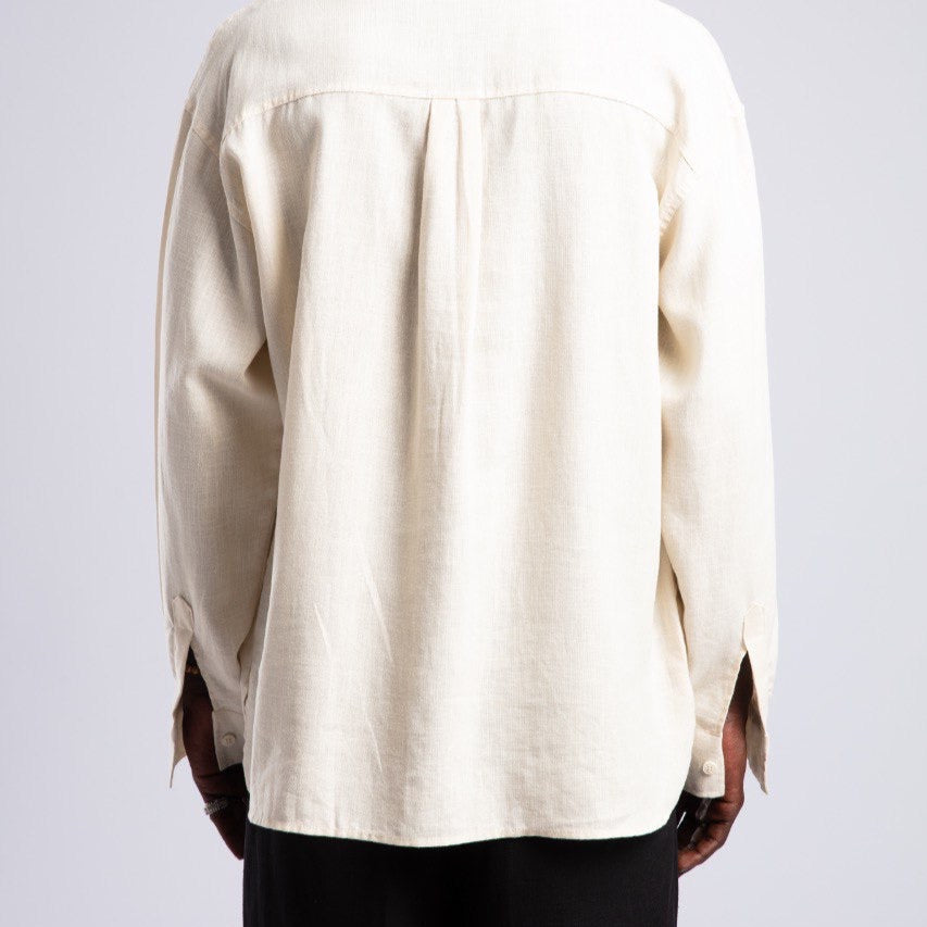 Person wearing a beige shirt from behind on a light gray background