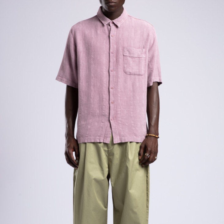 Man wearing a pink shirt and beige pants on a white background