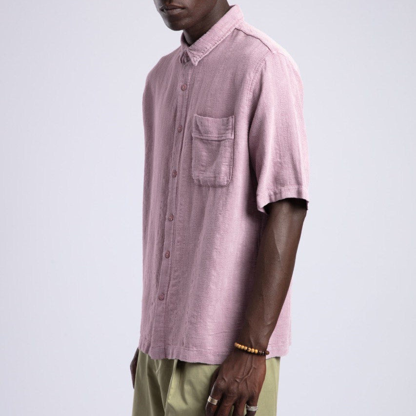 Man wearing a pink short-sleeve shirt and sunglasses on a white background