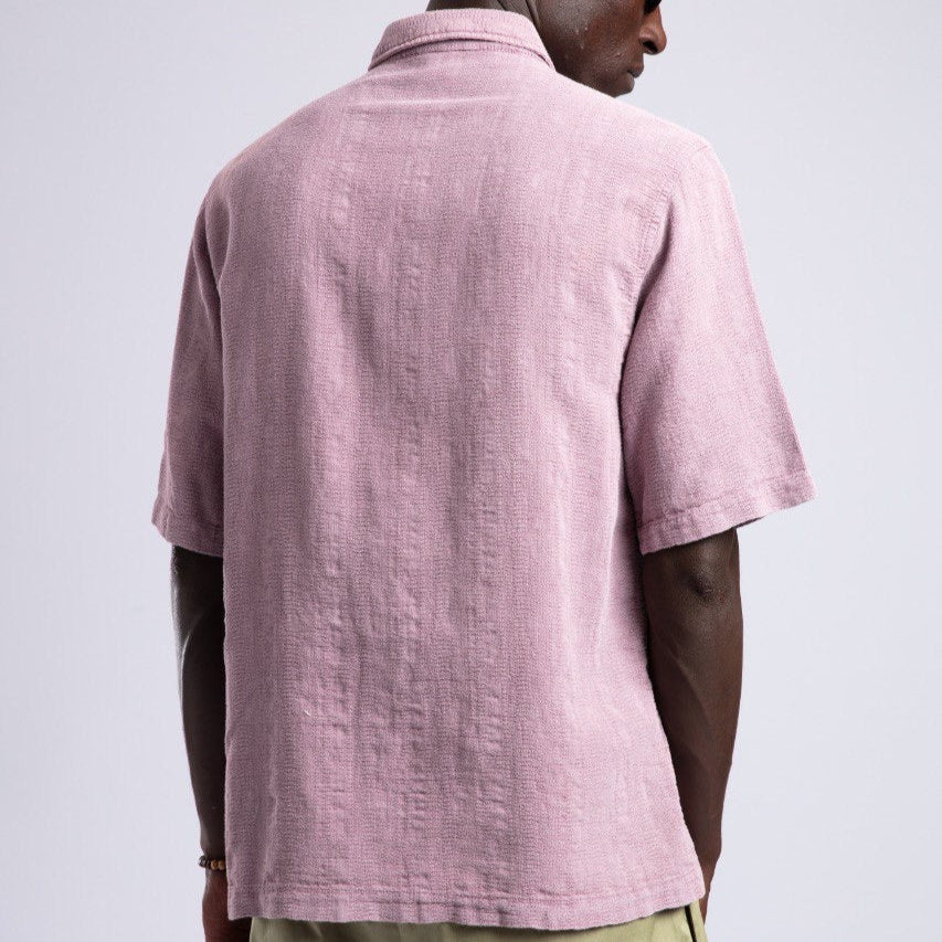 Man wearing a pink polo shirt and sunglasses on a light gray background