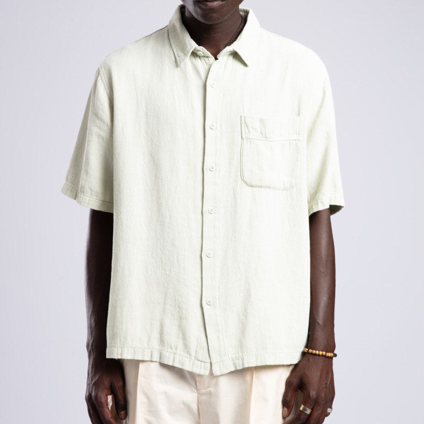 Man wearing a light-colored shirt and pants against a plain background