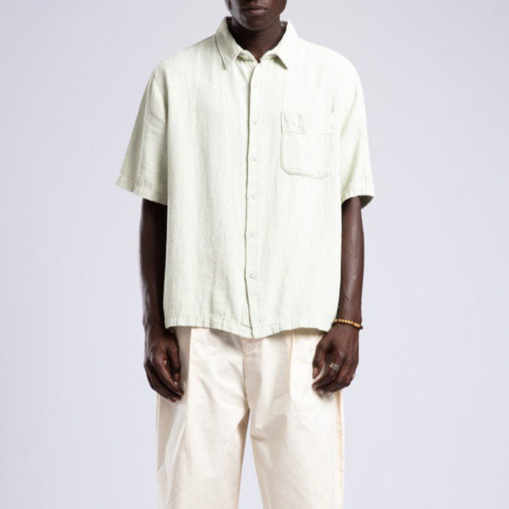 Man wearing a light-colored shirt and pants against a white background