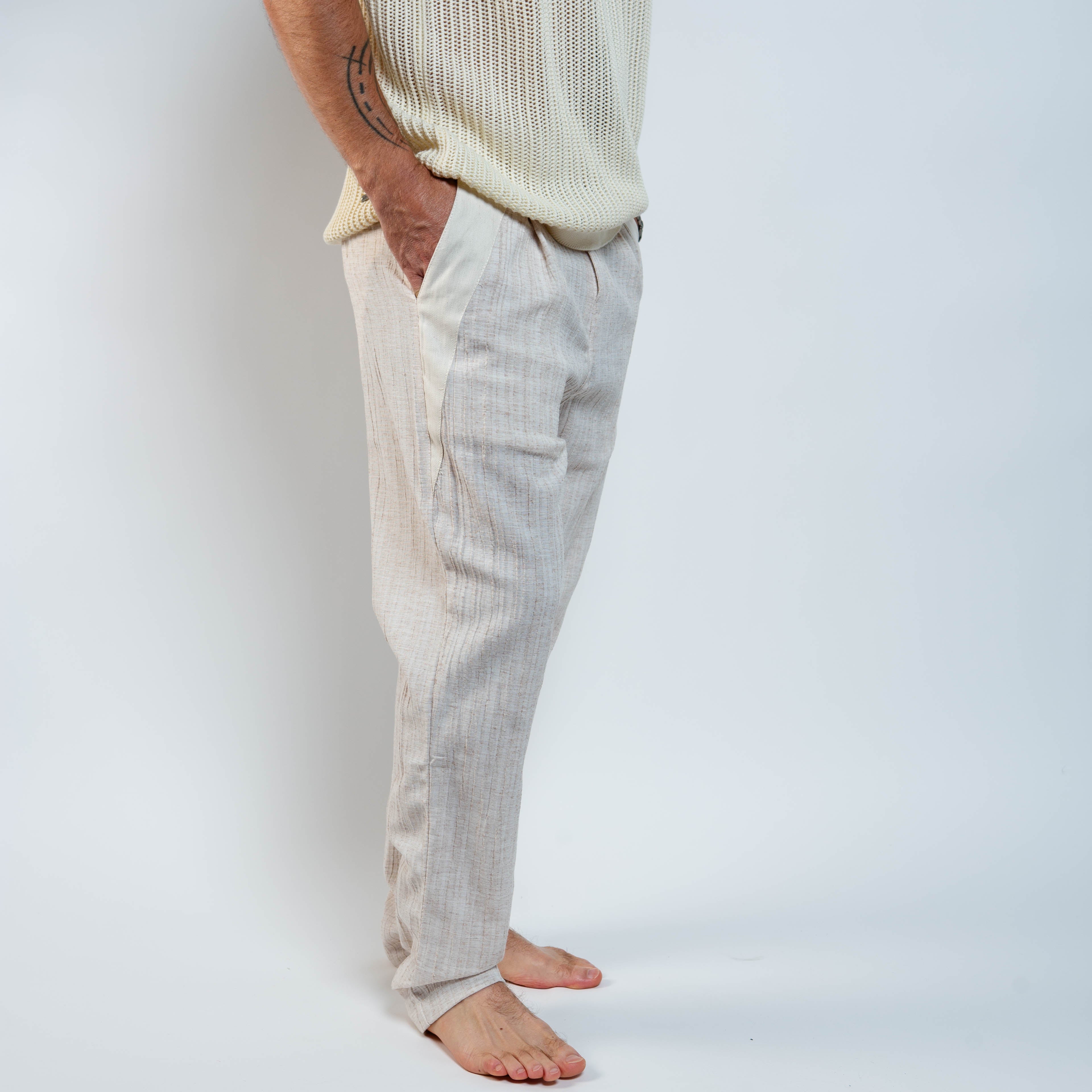 Person wearing light-colored pants and a cream sweater against a white background
