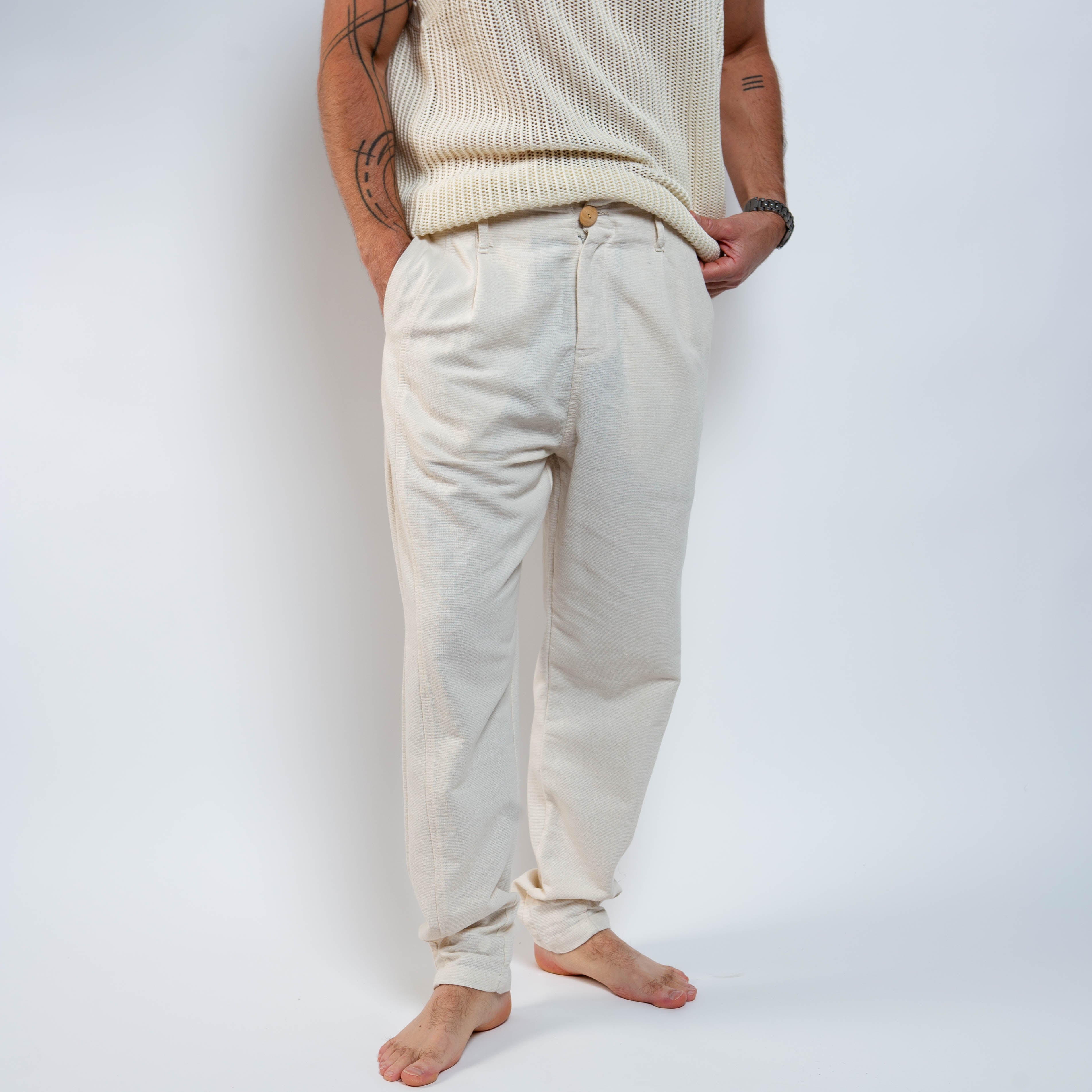 Person wearing a cream knit sweater and pants against a white background