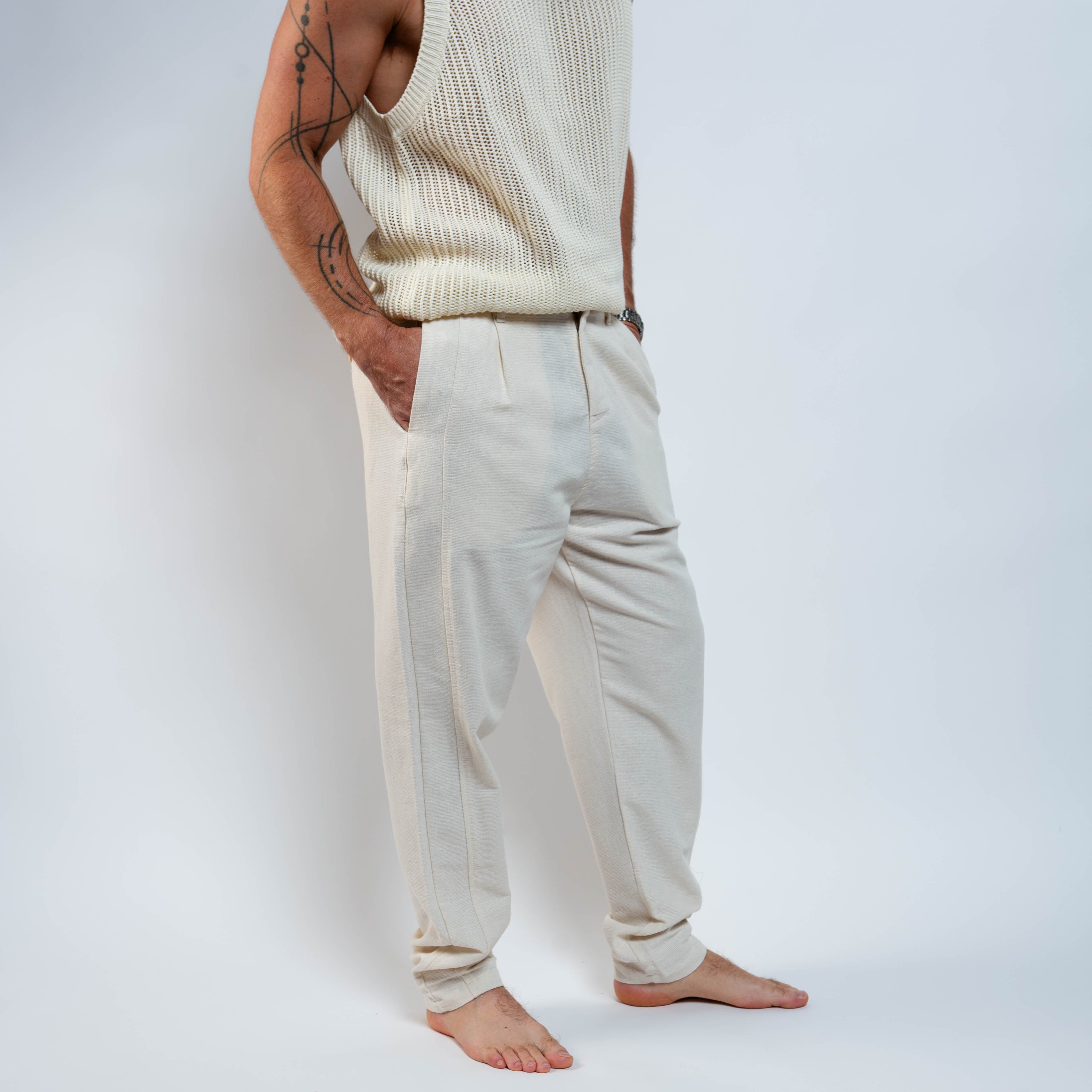 Person wearing a cream tank top and beige pants against a white background