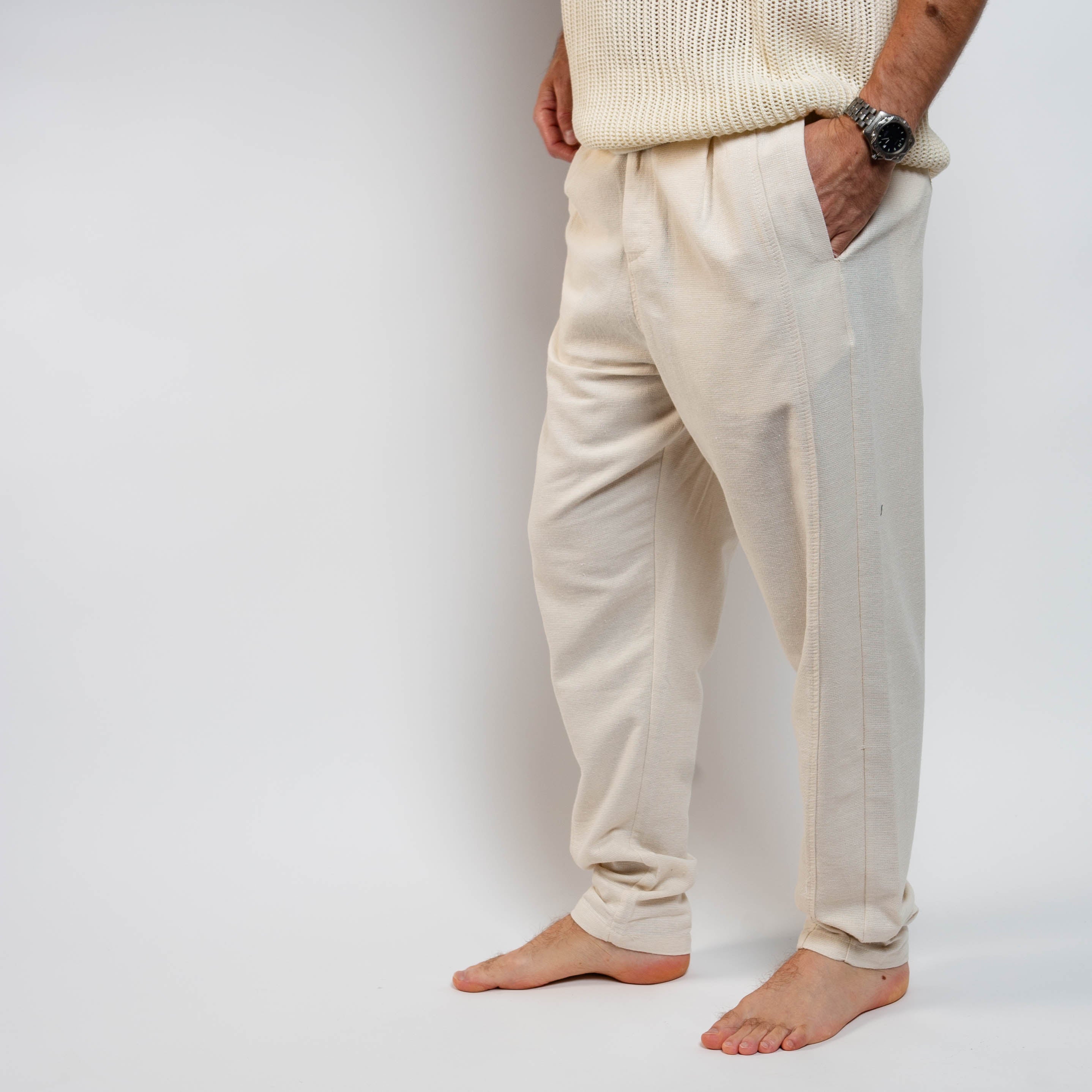 Person wearing beige pants and a cream sweater on a white background