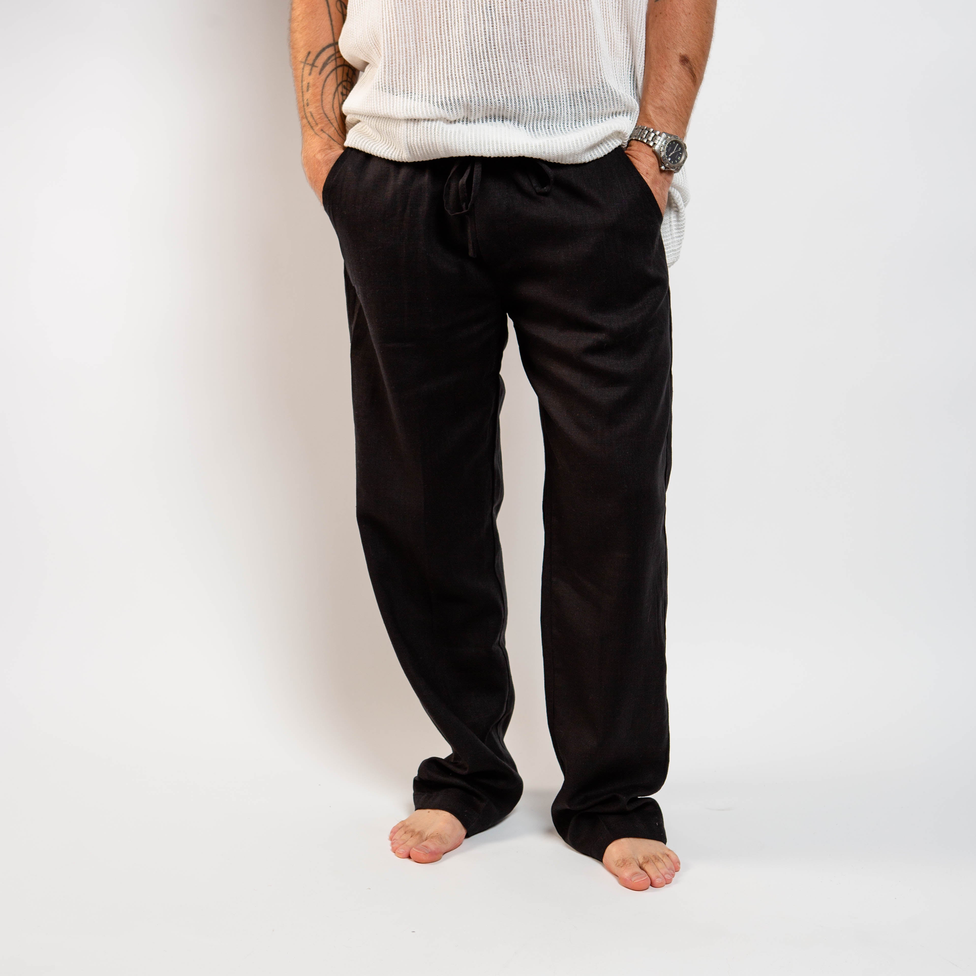Person wearing black pants and a white shirt on a plain background