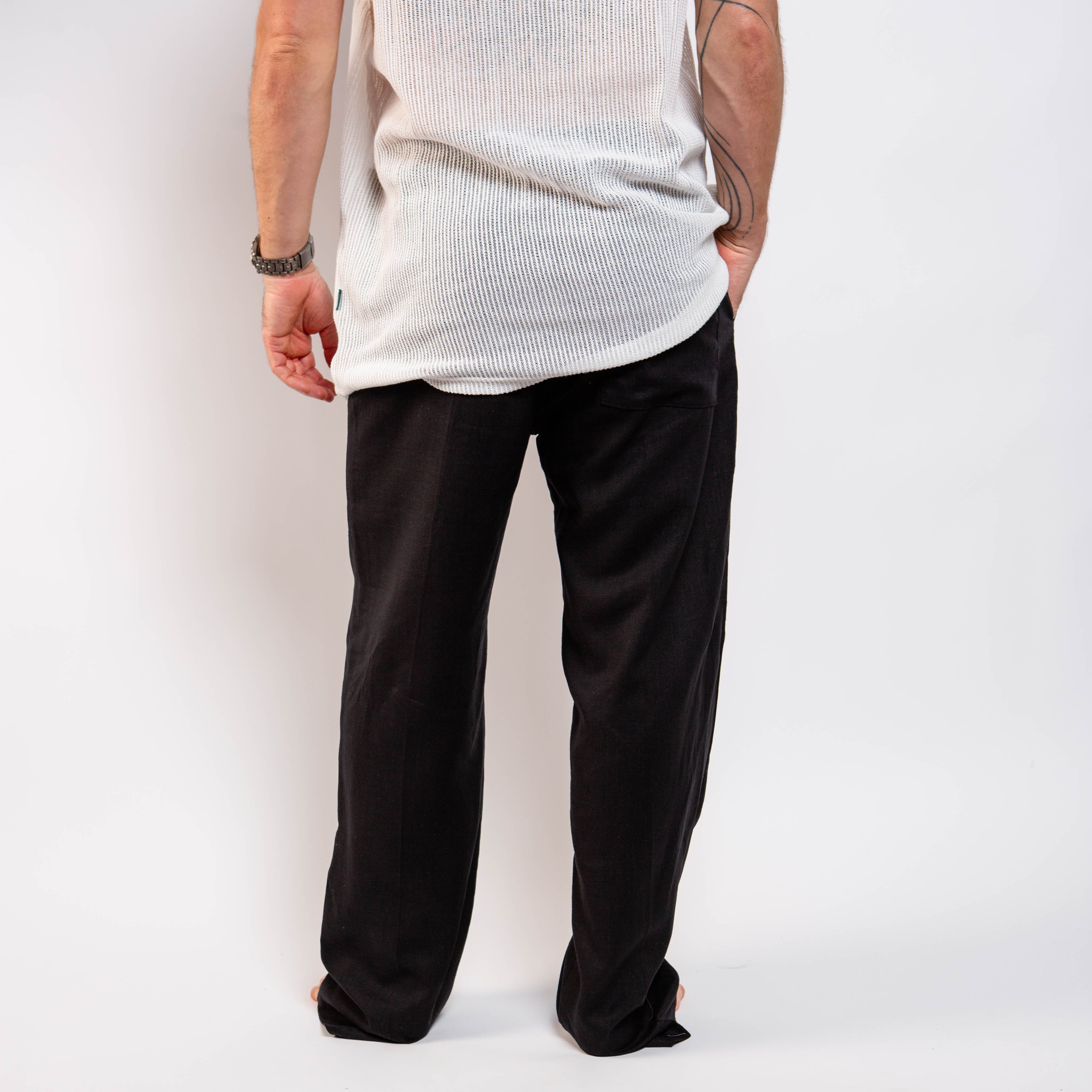 Person wearing a white shirt and black pants against a plain background