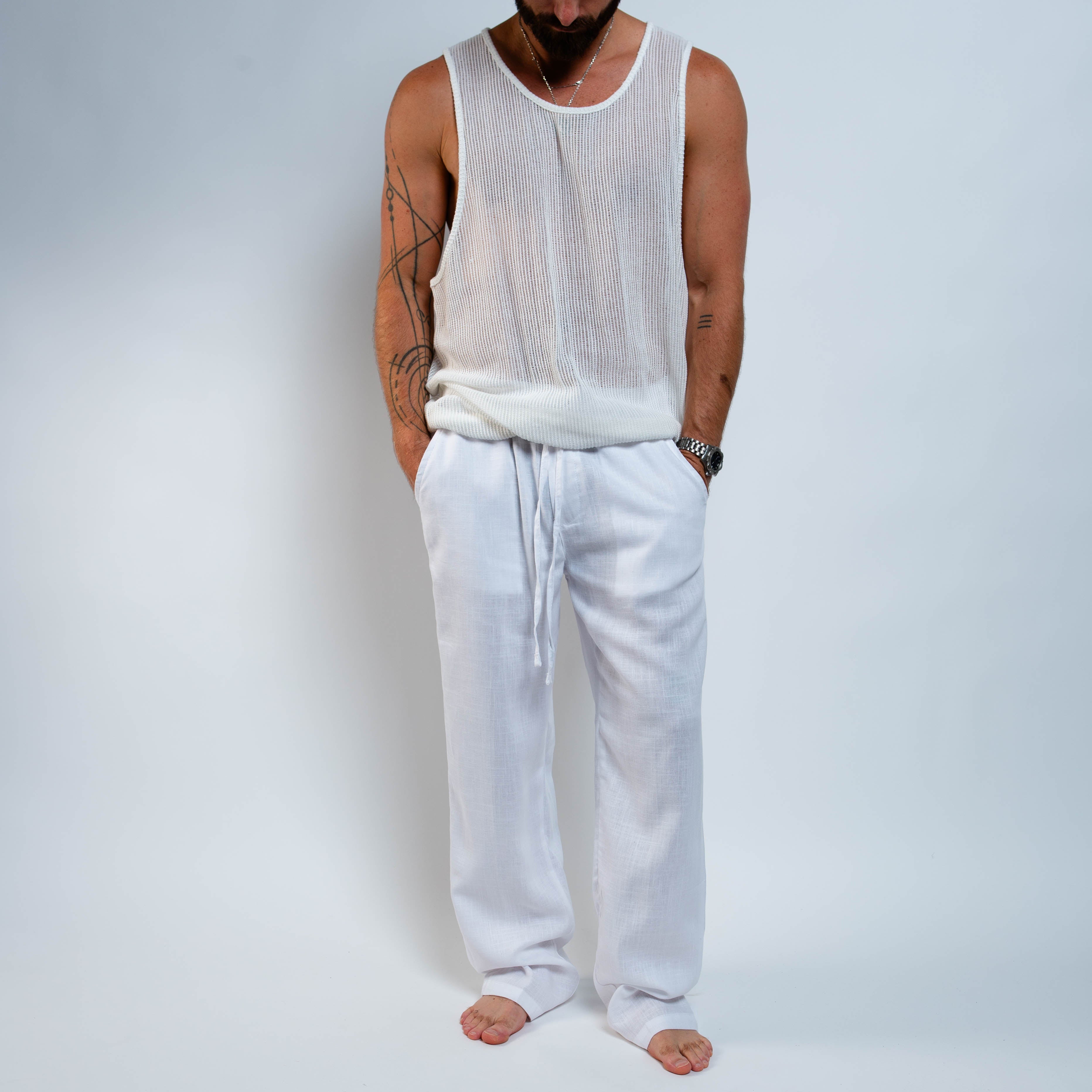 Person wearing a white tank top and light gray pants on a plain background