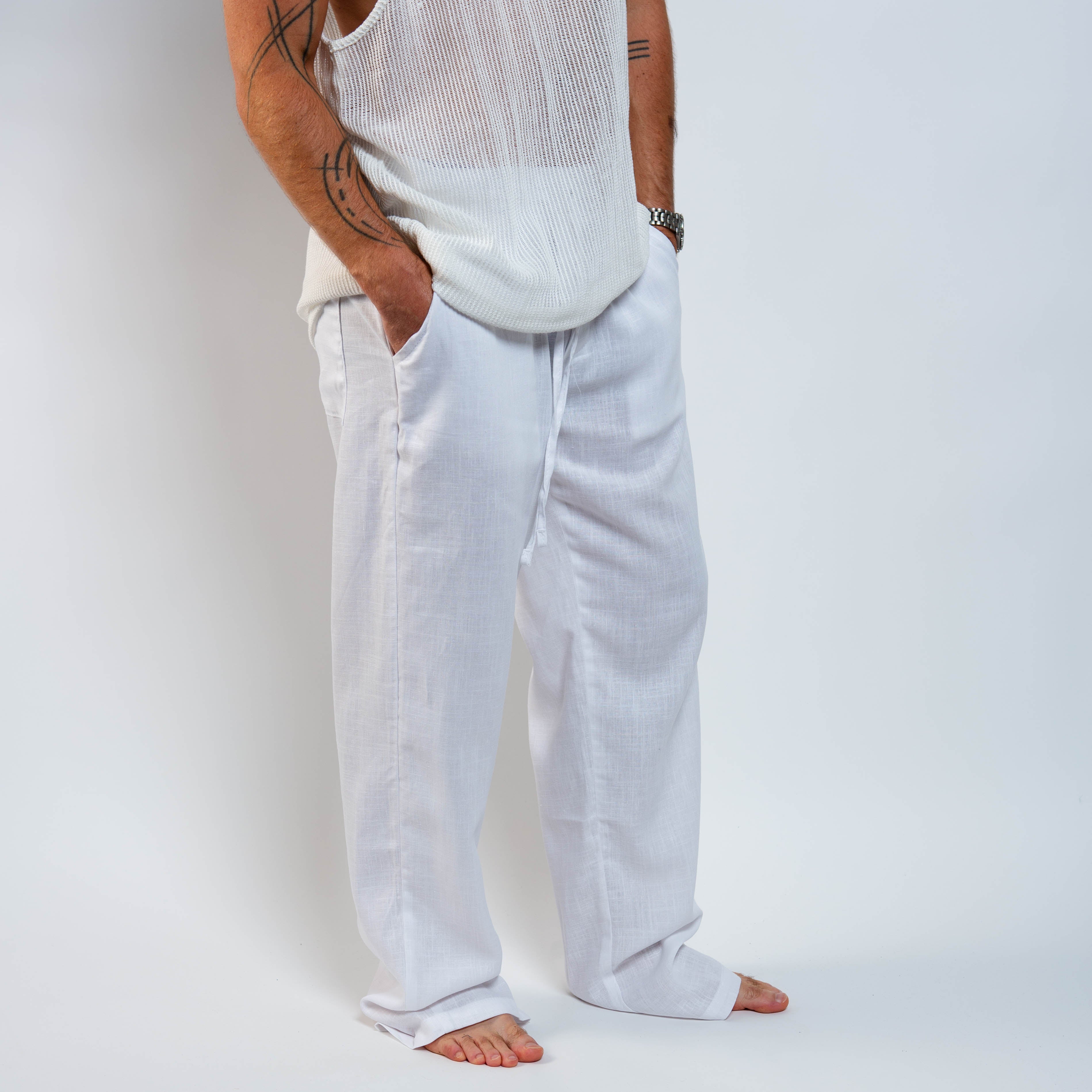 Person wearing light-colored pants and a sleeveless top against a plain background