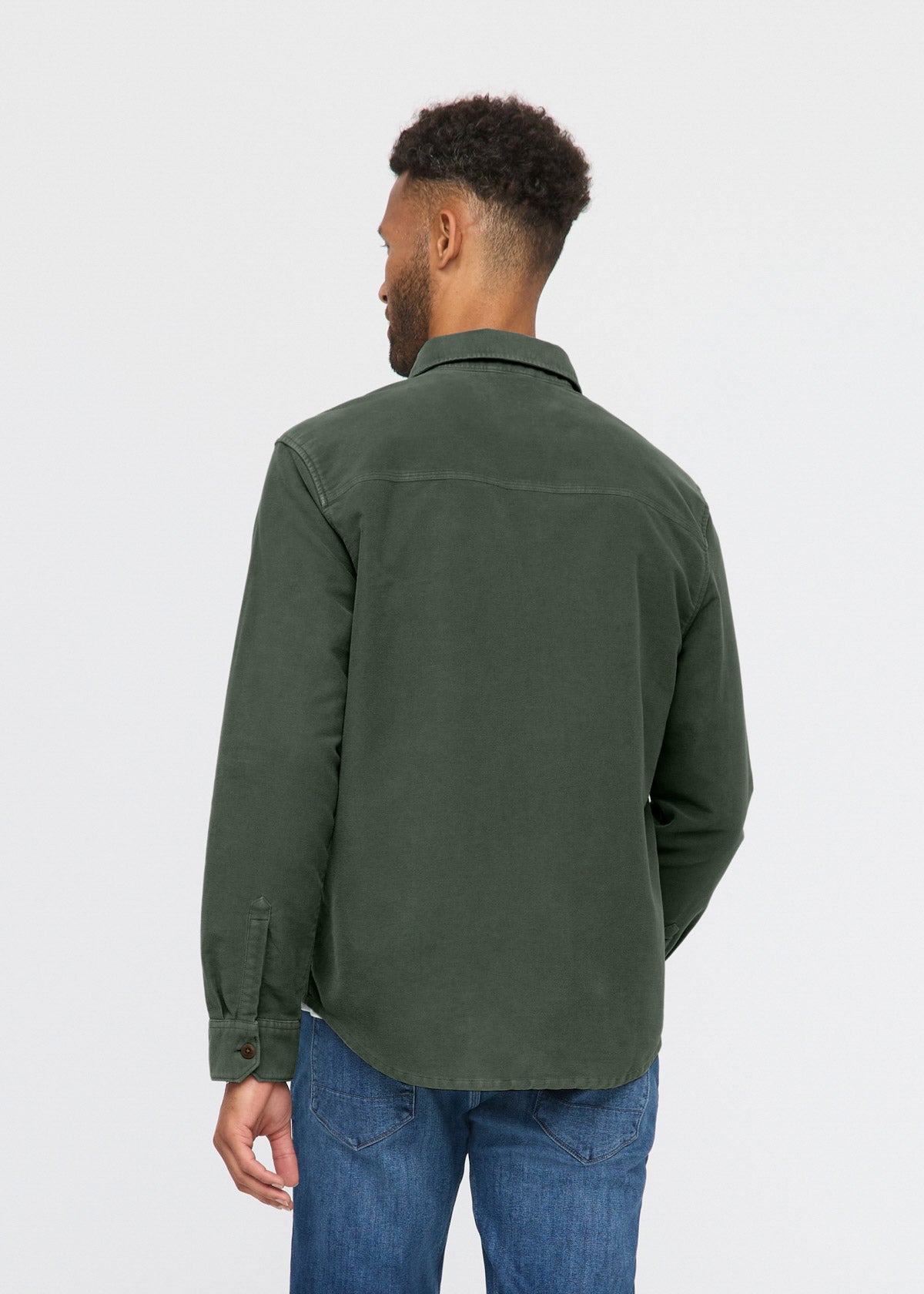 Man wearing a green jacket and blue jeans on a white background By Duer Jeans