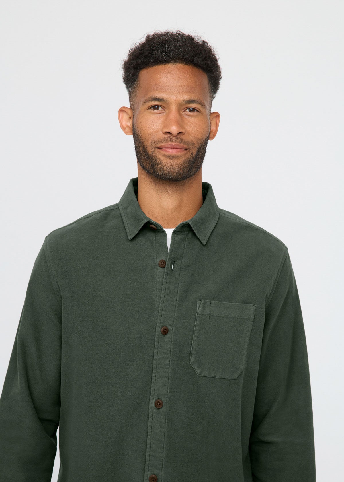Man wearing a green shirt against a plain background By Duer Jeans