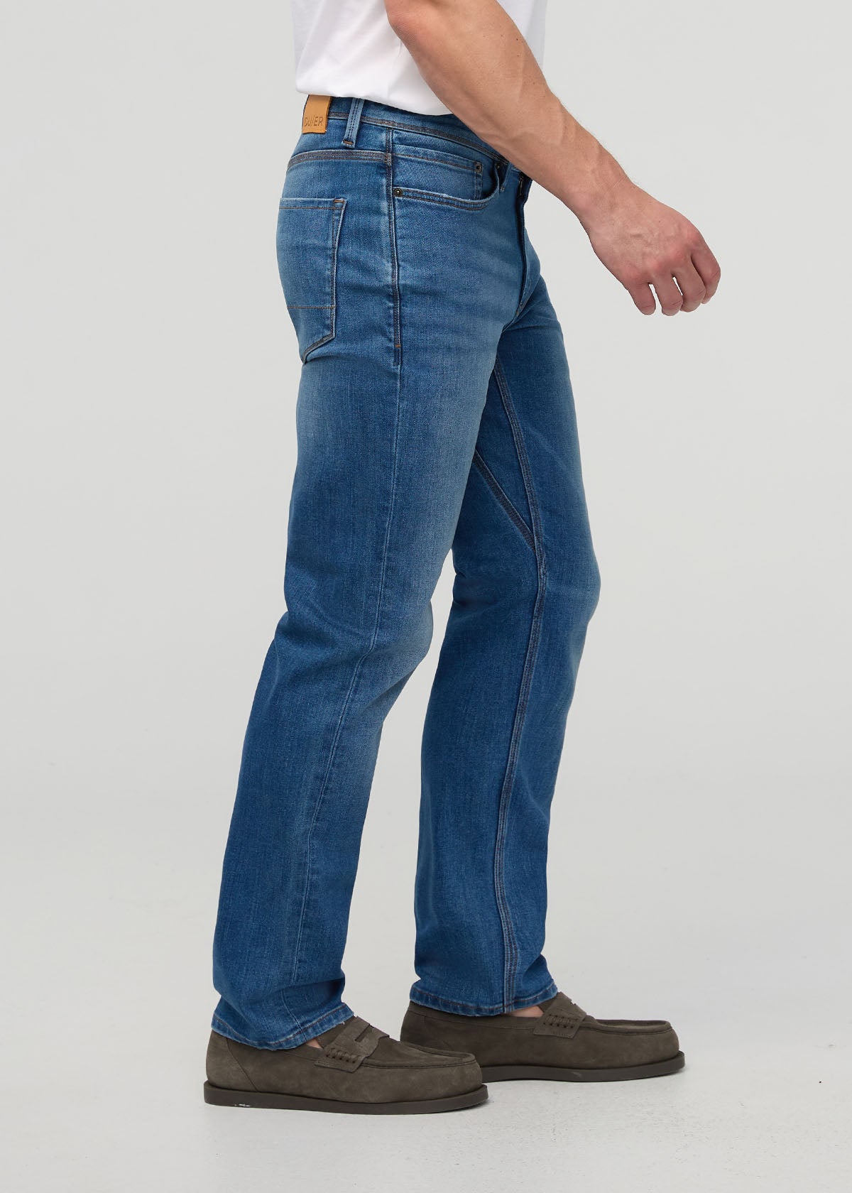 Person wearing blue jeans on a white background By Duer Jeans