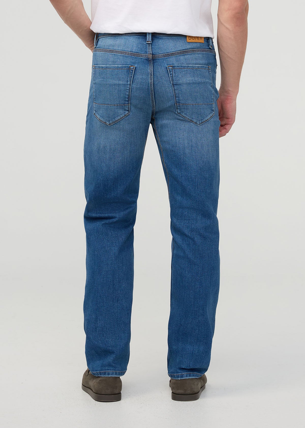 Person wearing blue jeans on a plain background By Duer Jeans