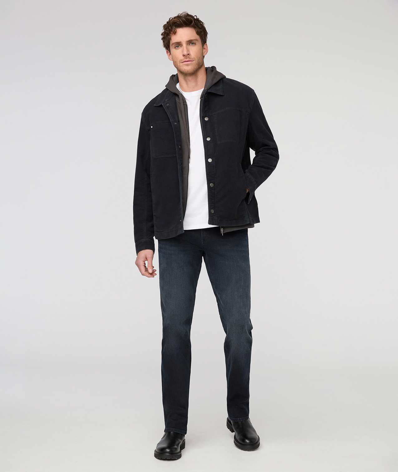 Man wearing a black jacket, white shirt, and dark jeans on a white background By Duer Jeans