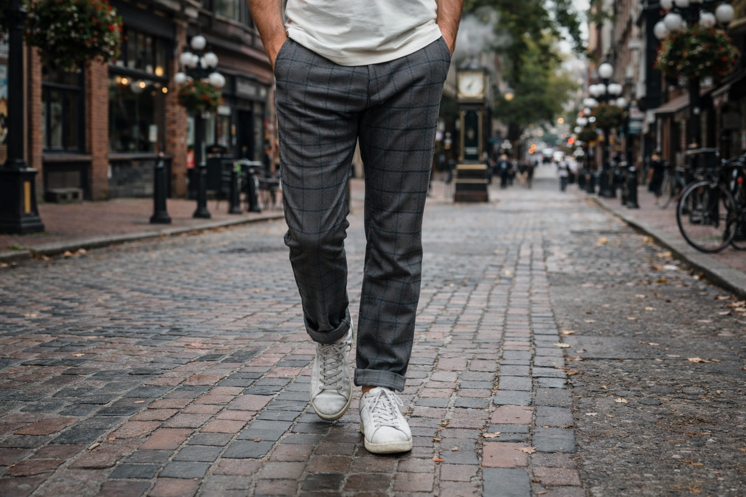male model wearing plaid mens pants walking down a cobblestone street in gastown vancouver wearing white sneakers