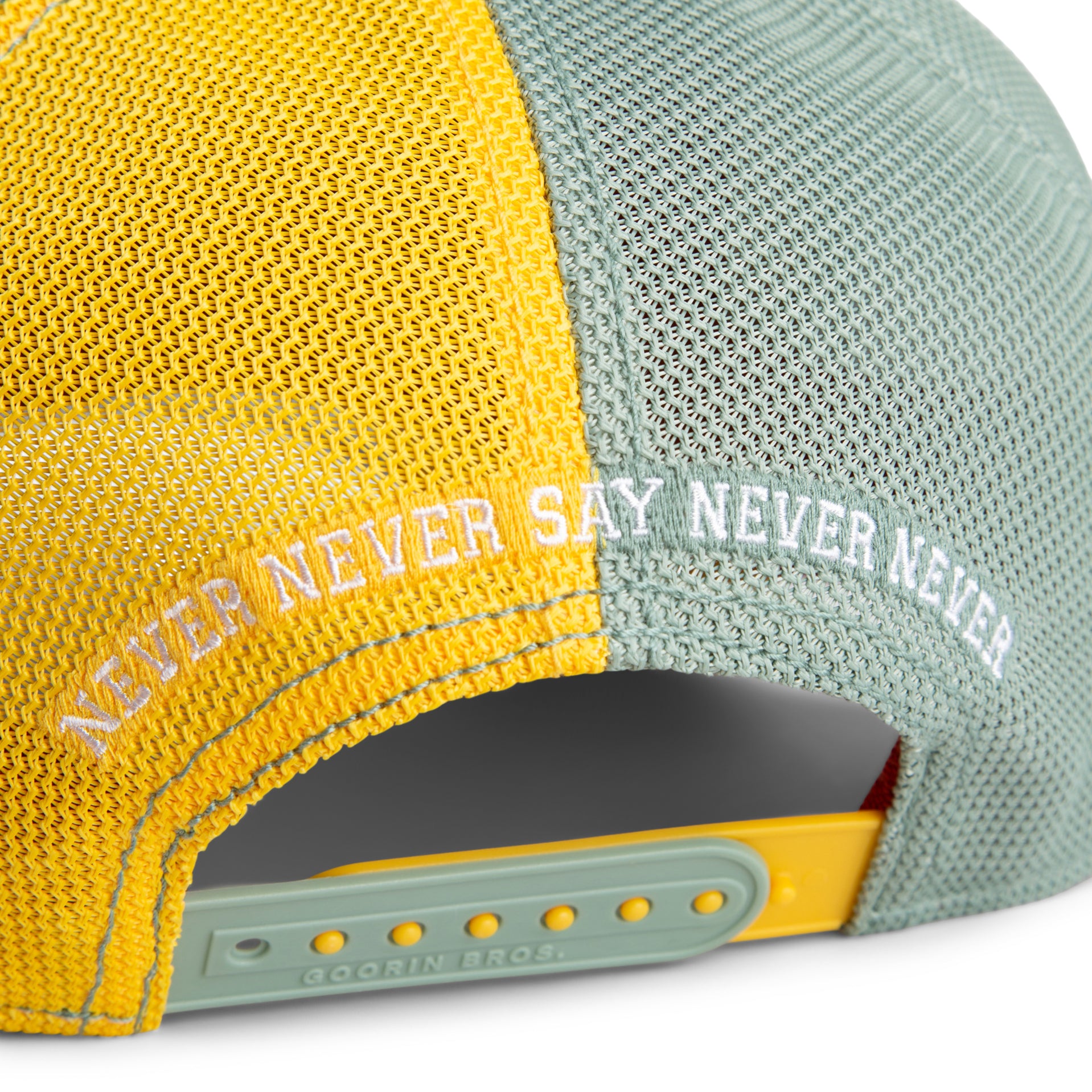Two-tone yellow and gray cap with 'NEVER NEVER SAY NEVER NEVER' text on a white background