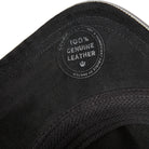Close-up of black leather with a '100% Genuine Leather' label on a white background