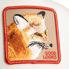 Beige and red Goorin Bros trucker hat with mesh back featuring embroidered fox patch labeled GOOD LOOKS on front panel
