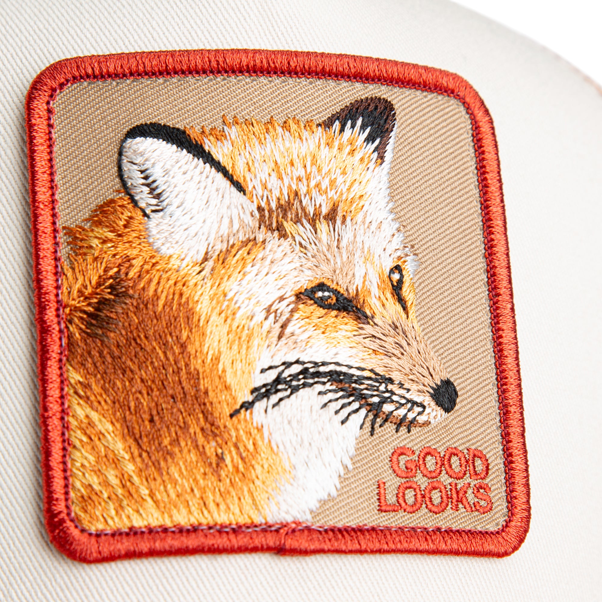 Beige and red Goorin Bros trucker hat with mesh back featuring embroidered fox patch labeled GOOD LOOKS on front panel
