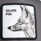 Grey Goorin Bros trucker hat with mesh back featuring embroidered fox patch labeled SILVER FOX on front panel

