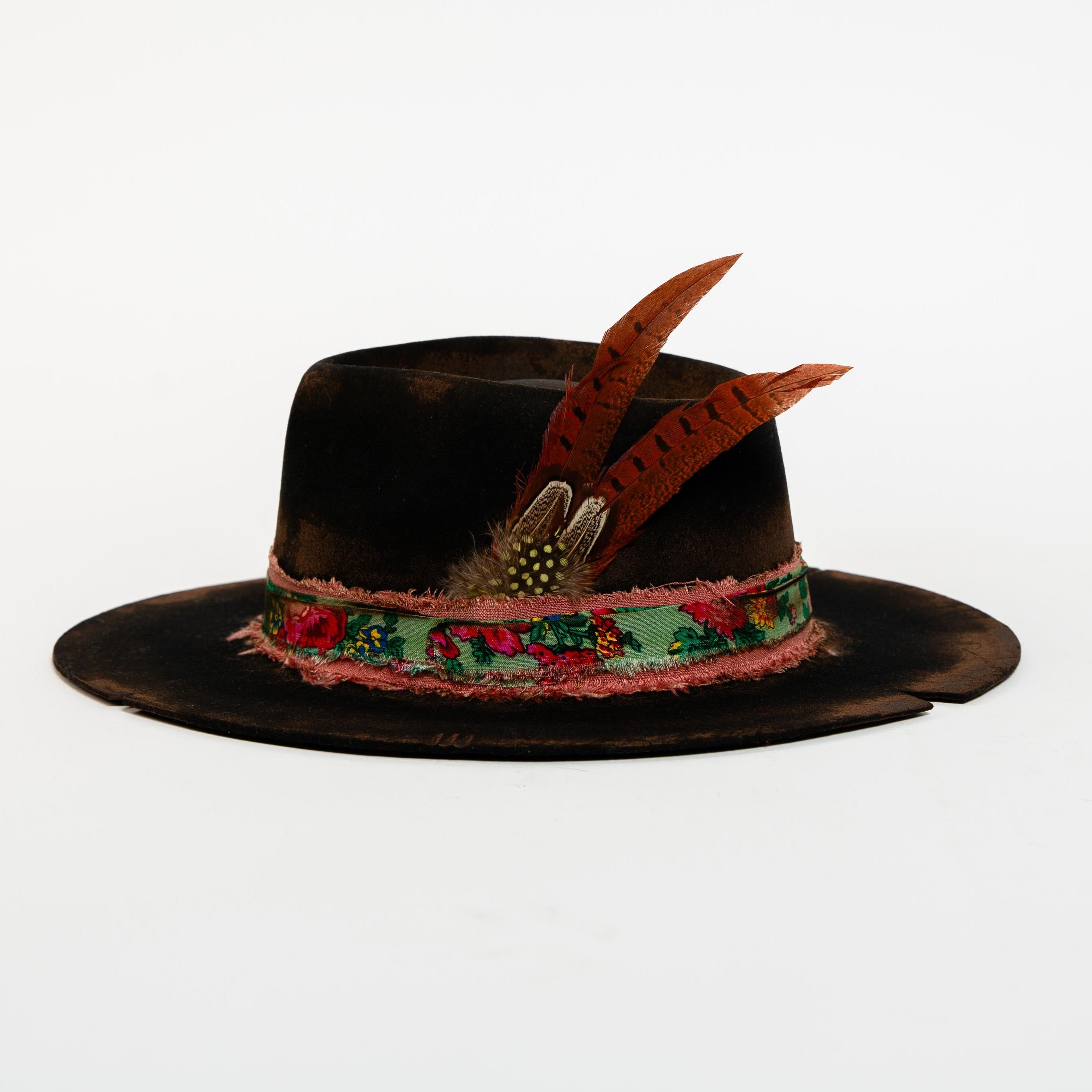 Black hat with decorative band and feathers on a white background