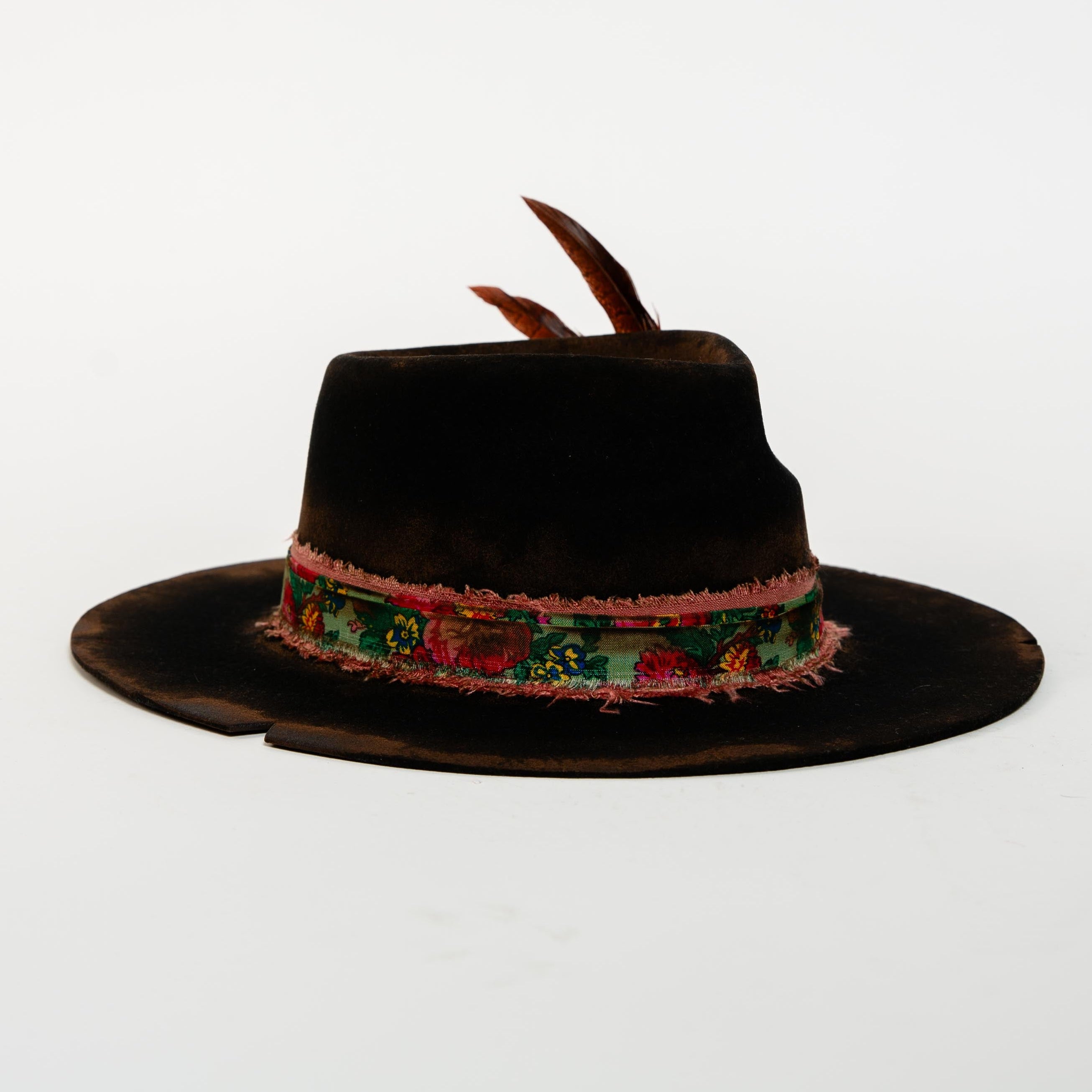 Black hat with a decorative band and feathers on a white background
