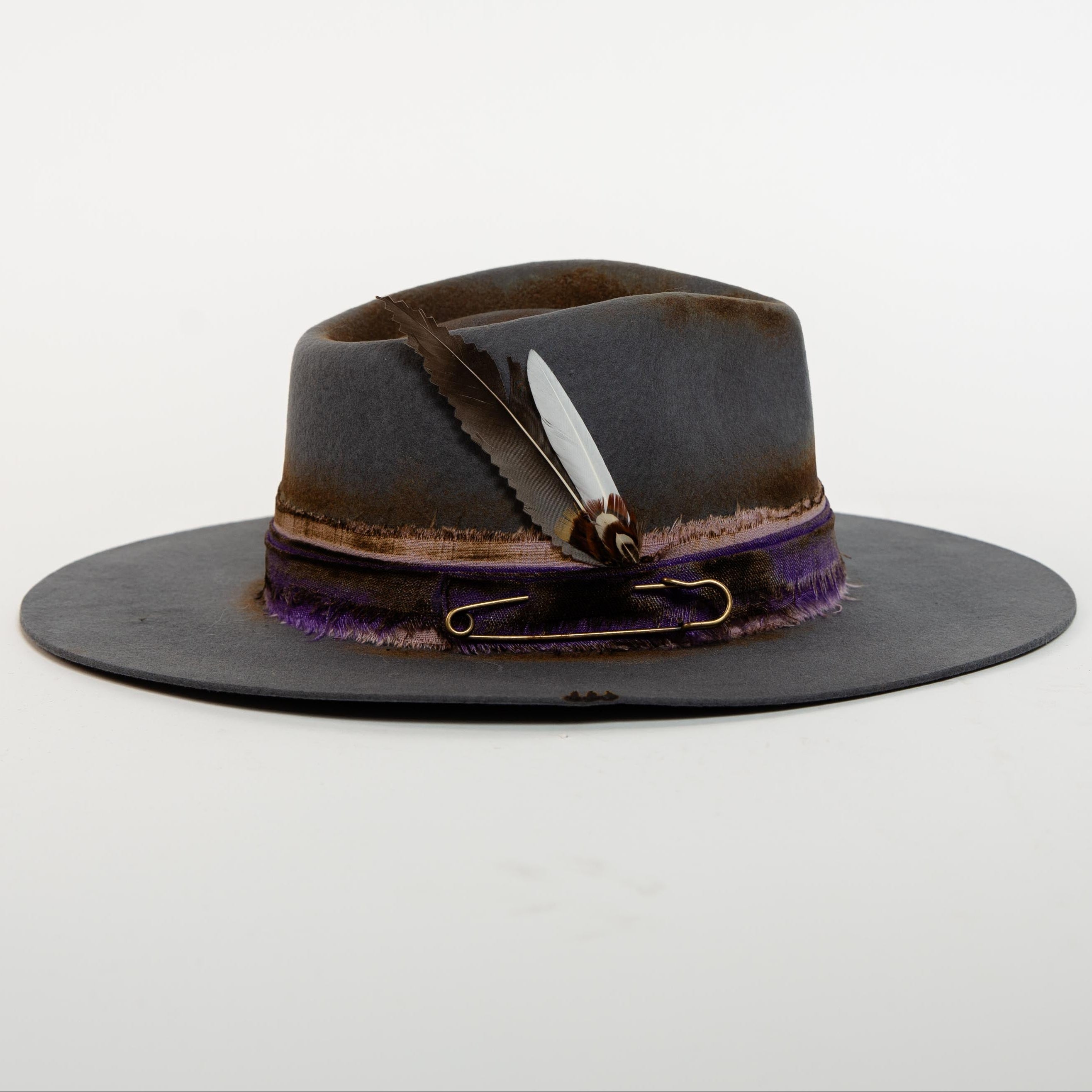 Brown and black hat with feather and ribbon on a white background
