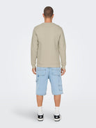 Person wearing a beige sweatshirt and light blue shorts on a white background By Only & Sons