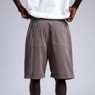 Person wearing brown shorts, white socks, and white sneakers on a plain background
