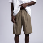 Person wearing beige shorts and white sneakers on a plain background