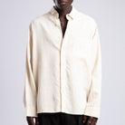 Man wearing a cream shirt and sunglasses on a plain background