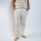 Person wearing a cream knit sweater and pants against a white background